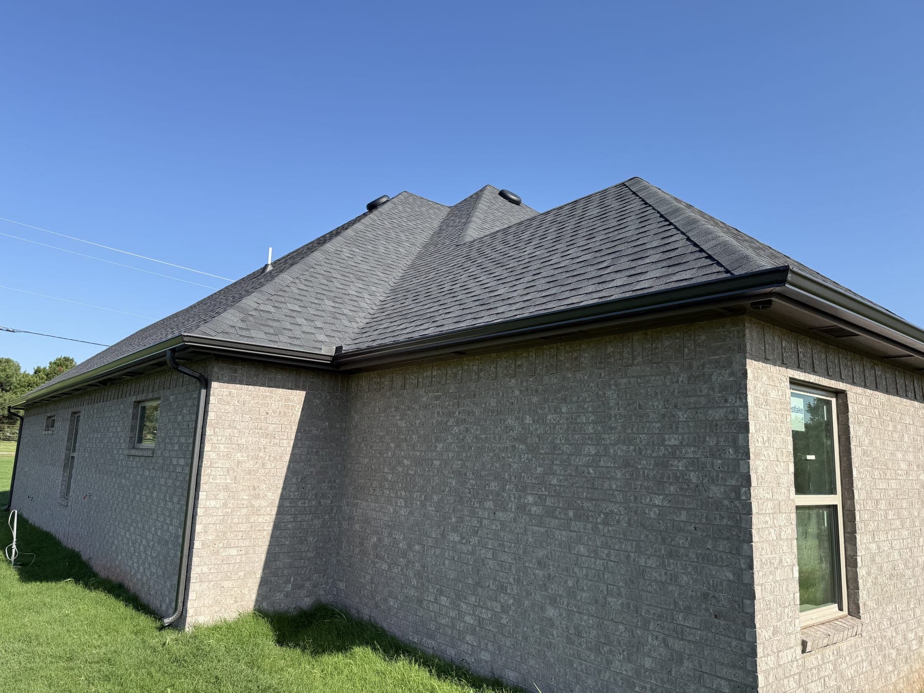 Seamless gutters custom-fit to the hip roof of a brick home in Oklahoma City, OK